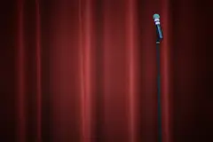 A mic stand in front of a red curtain