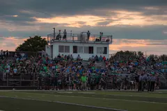 A high school game at sunset: the home stands and press box
