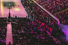 A packed arena under pink and purple lights (cropped to the lower bowl)